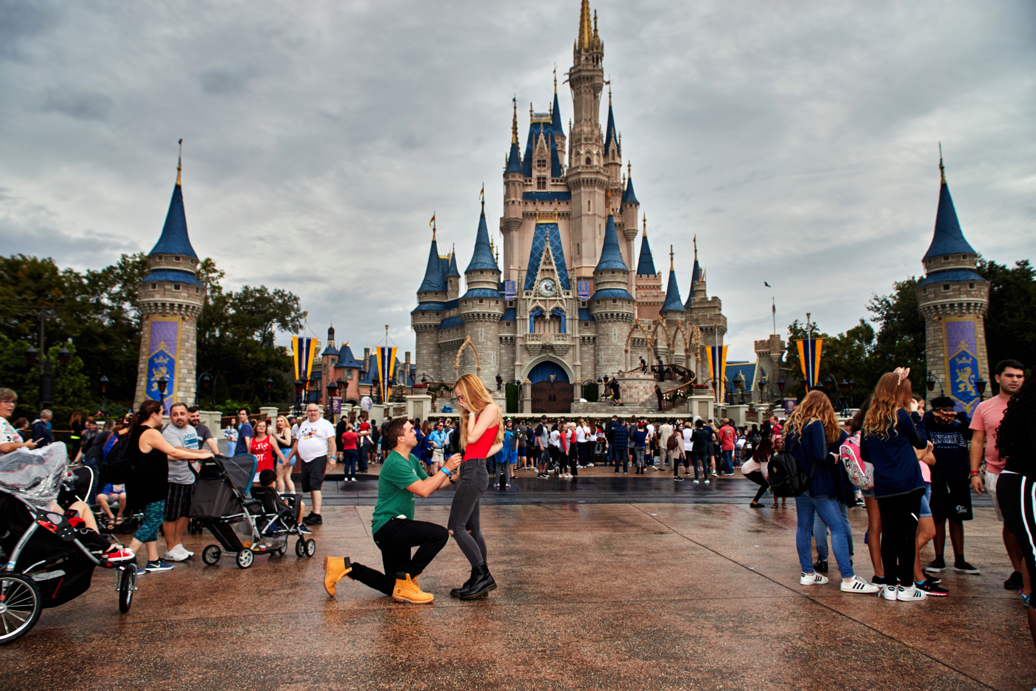 Young man proposes to a young woman in front of the castle at the magic kingdom