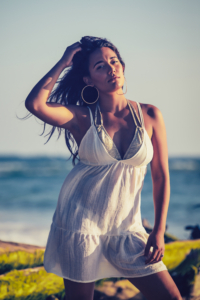 girl stand on the beach in front of a fallen tree