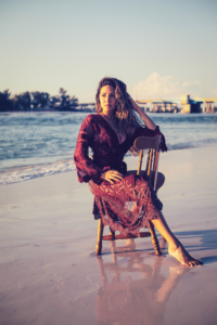 young woman sits in a chair at the beach