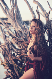 Young woman stands in front of a fallen tree at the beach