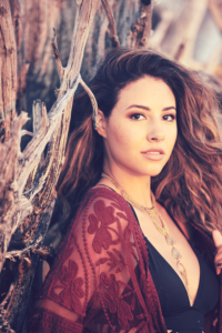 Young woman stands in front of a fallen tree at the beach