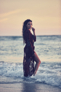 Young Woman stands at the waters edge during sunset