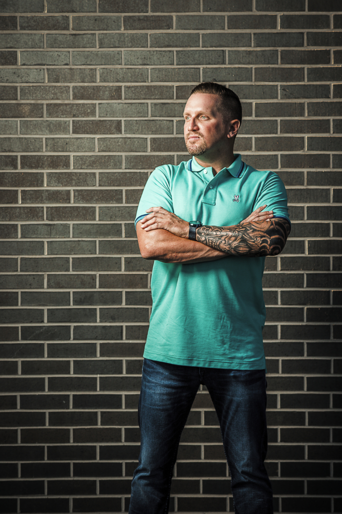 man stands in front of a brick wall